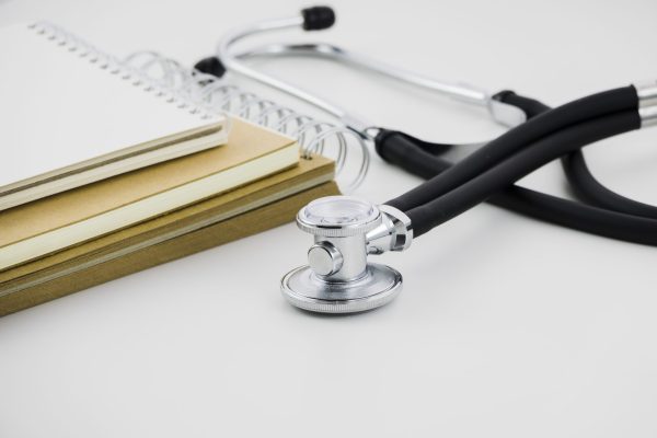 stack-spiral-notepad-stethoscope-white-backdrop
